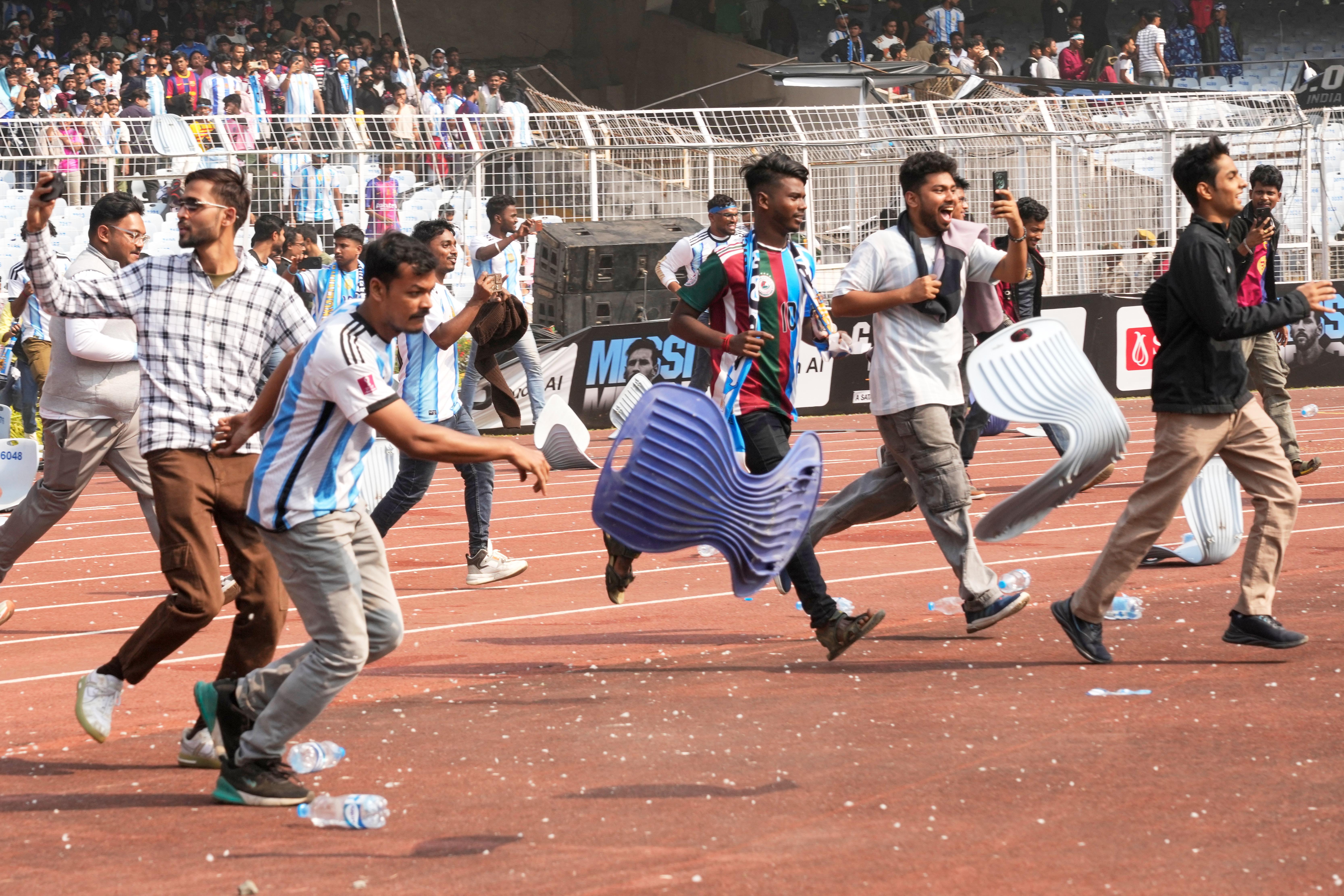 India_Lionel_Messi_49586 Indian fans vandalize stadium chairs as they run on to the field after failing to get a glimpse of Argentine soccer star Lionel Messi at the Salt Lake Stadium, in Kolkata, India, Saturday, Dec. 13, 2025. (AP Photo/Bikas Das)
