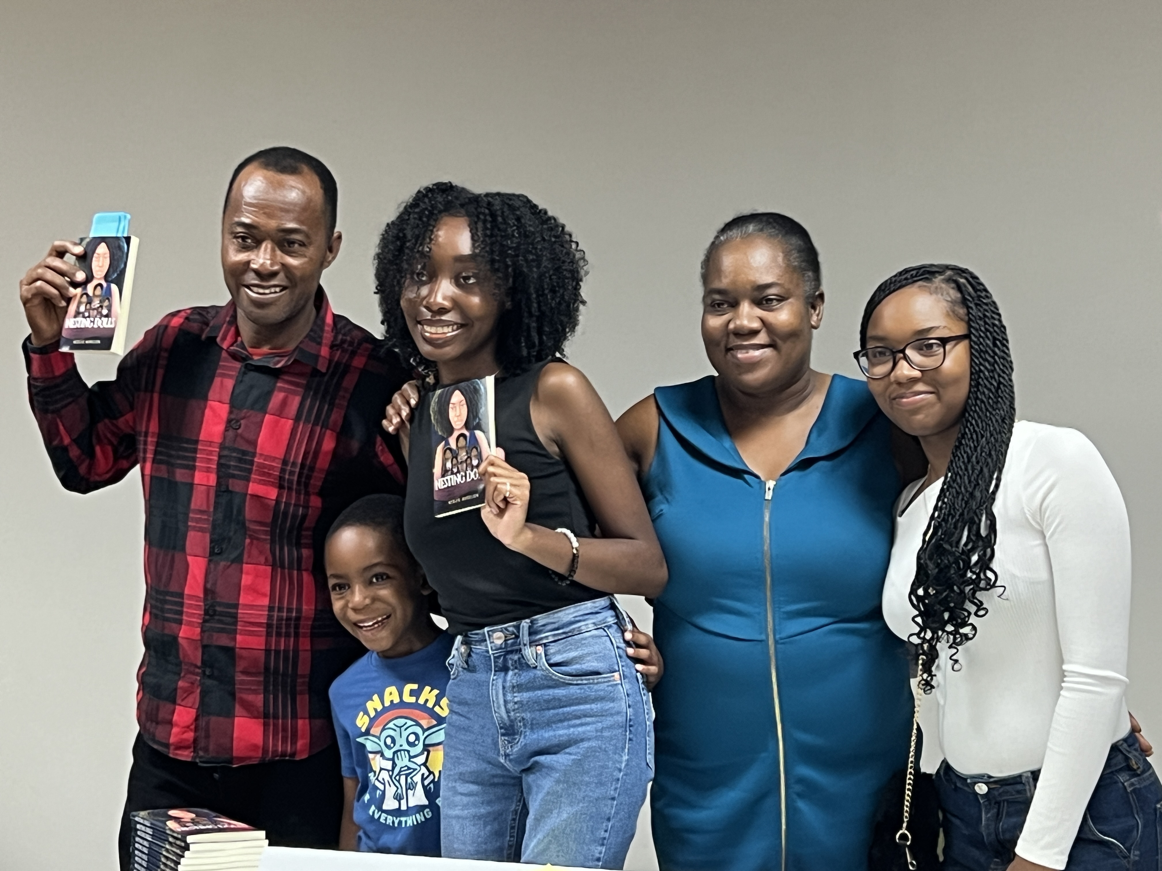 Nedjie Aurelien and her family hold up copies of "Nesting Dolls," her poetry collection. (courtesy, Nedjie Aurelien)